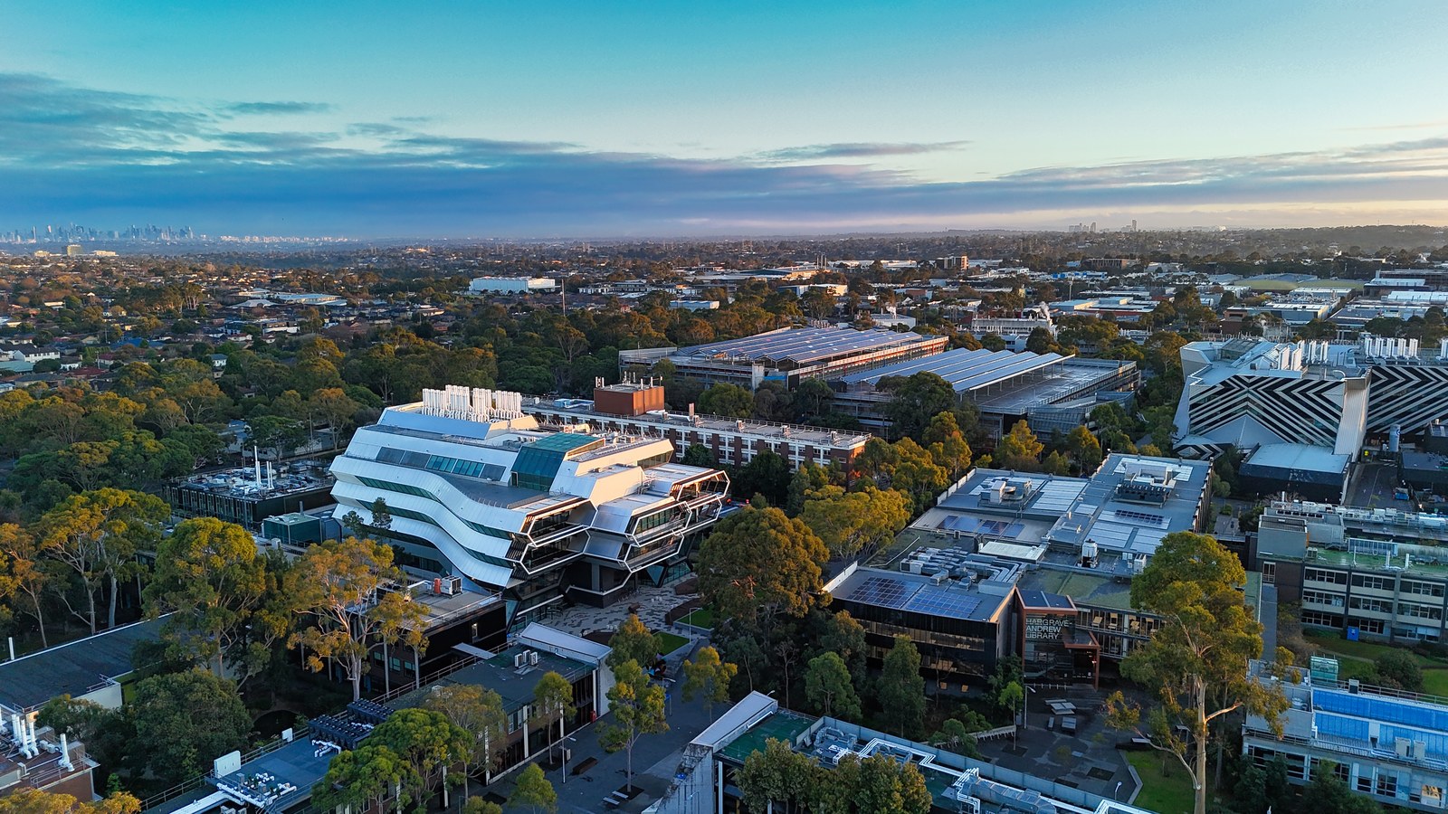 An elevated view of tree-lined buildings, including a prominent white building with angular stacked levels.
