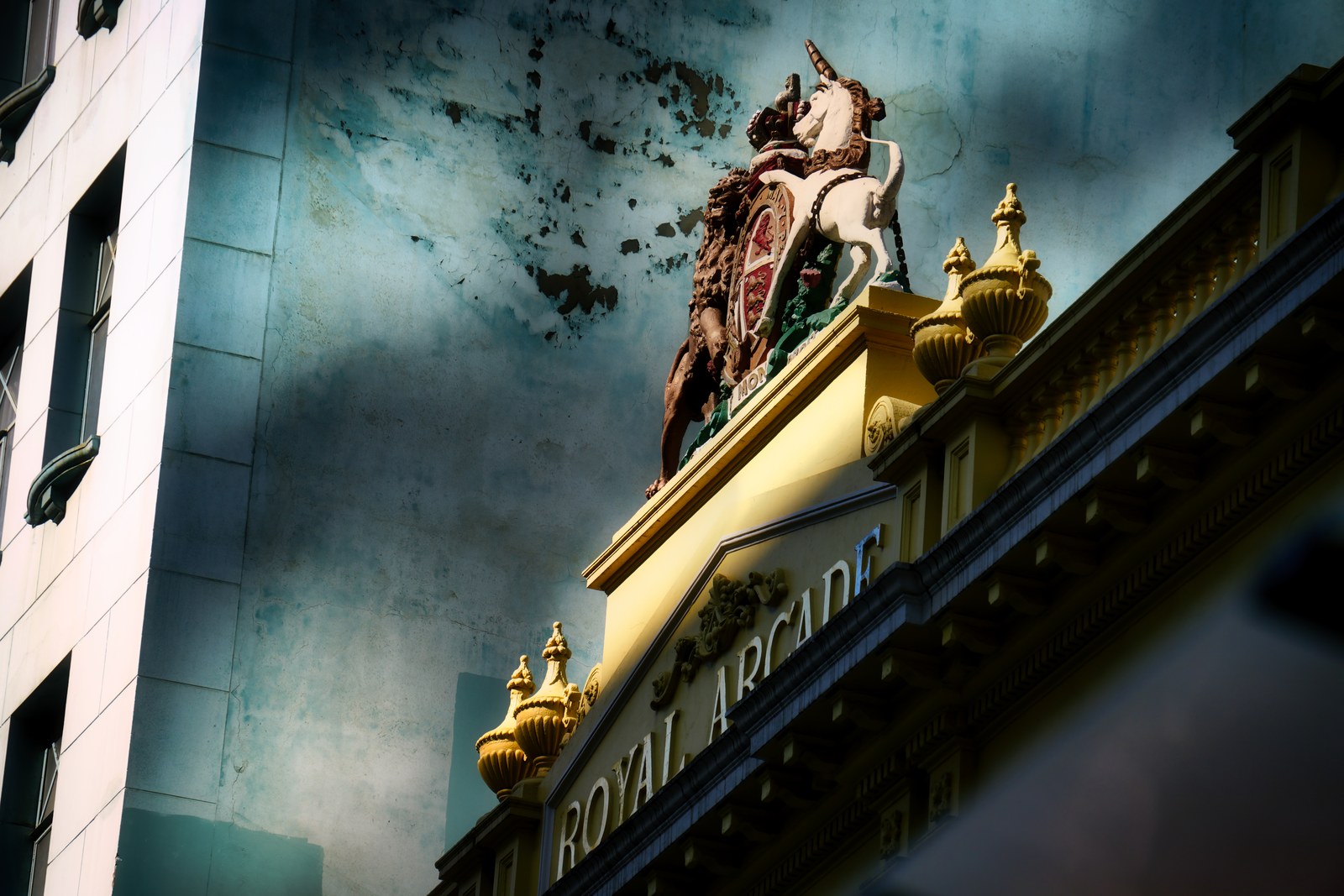 An ornate gold-and-red building entrance marked Royal Arcade stands against a weathered blue wall.